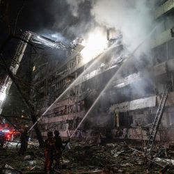 Bomberos ucranianos extinguen un incendio en el lugar donde impactó un misil ruso contra un edificio de apartamentos en Kiev, en el contexto de la invasión rusa de Ucrania. | Foto:GENYA SAVILOV / AFP