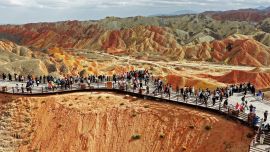 Imagen tomada con un dron de turistas visitando el área escénica de Zhangye Danxia caracterizada por llamativas formaciones de arenisca roja, en Zhangye, en la provincia de Gansu, en el noroeste de China.