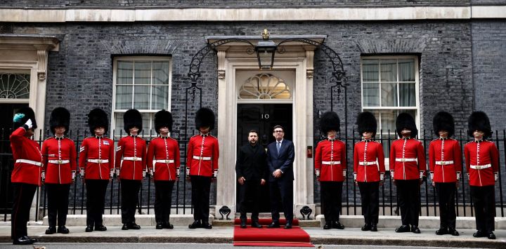 El primer ministro británico, Andy Burnham (derecha), saluda al presidente de Ucrania, Volodímir Zelenski, flanqueado por miembros de la 12.ª compañía de la Guardia Irlandesa (Irish Guards), en la escalinata del número 10 de Downing Street, en el centro de Londres, antes de su reunión.