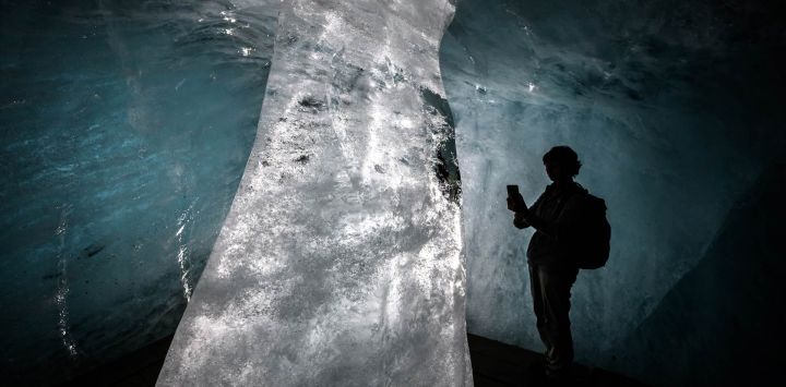 Esta fotografía muestra a un turista tomando imágenes de una columna de hielo en el interior de una cueva —ahora mucho más pequeña— del glaciar del Ródano, en los Alpes suizos, cerca de Gletsch. Tras el calor extremo de junio y julio, el glaciar del Ródano ha perdido más de cuatro metros de hielo en un solo mes, según el glaciólogo Matthias Huss, director de la Red Suiza de Monitoreo de Glaciares (GLAMOS), citado por la agencia de noticias suiza Keystone-SDA. El retroceso del glaciar, que promedia unos 10 centímetros diarios, ha generado preocupación de que 2026 pueda igualar la pérdida de hielo récord registrada en 2022.