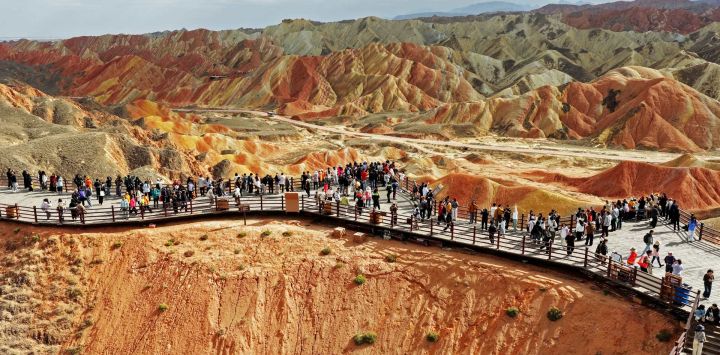 Imagen tomada con un dron de turistas visitando el área escénica de Zhangye Danxia caracterizada por llamativas formaciones de arenisca roja, en Zhangye, en la provincia de Gansu, en el noroeste de China.