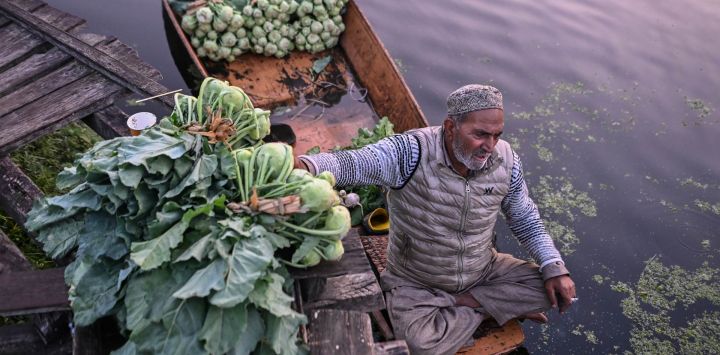 Un comerciante de vegetales vende su producto en un barco por la mañana en un mercado de vegetales flotante, en el lago Dal, en Srinagar, capital de verano de Cachemira.