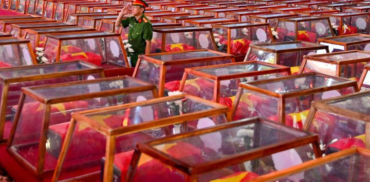 Un soldado hace el saludo militar mientras permanece de pie entre ataúdes que contienen los restos de soldados caídos, en el parque Le Thi Rieng de la ciudad de Ho Chi Minh. Vietnam celebró los ritos funerarios de más de 700 de sus caídos en combate, cuyos restos fueron exhumados en el marco de una importante iniciativa destinada a identificar a los desaparecidos durante décadas de conflicto con Francia y Estados Unidos.