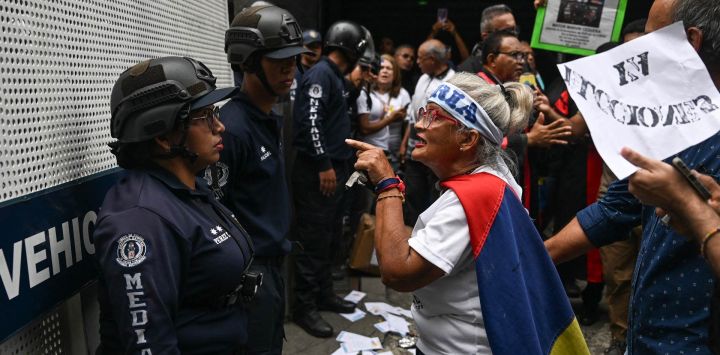 Una mujer que porta una bandera venezolana se enfrenta a un agente de policía durante una marcha de trabajadores —en activo y jubilados— de los sectores de salud y educación, junto a familiares de presos políticos, quienes exigen un aumento salarial y la liberación de los presos políticos, cerca del palacio presidencial de Miraflores, en Caracas.