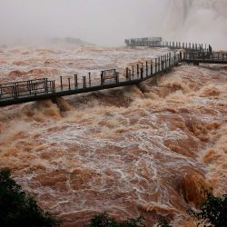 Una vista general muestra la pasarela para visitantes en las cataratas del Iguazú, situada sobre una fuerte corriente, vista desde el lado brasileño —en la triple frontera entre Brasil, Argentina y Paraguay—, en la ciudad de Foz do Iguaçu, estado de Paraná, Brasil. Las autoridades cerraron temporalmente el acceso turístico a las cataratas del Iguazú debido a la crecida del río homónimo; asimismo, se ha registrado un aumento en el caudal de los ríos Paraná y Uruguay, consecuencia de las lluvias asociadas al fenómeno de El Niño. | Foto:CHRISTIAN RIZZI / AFP