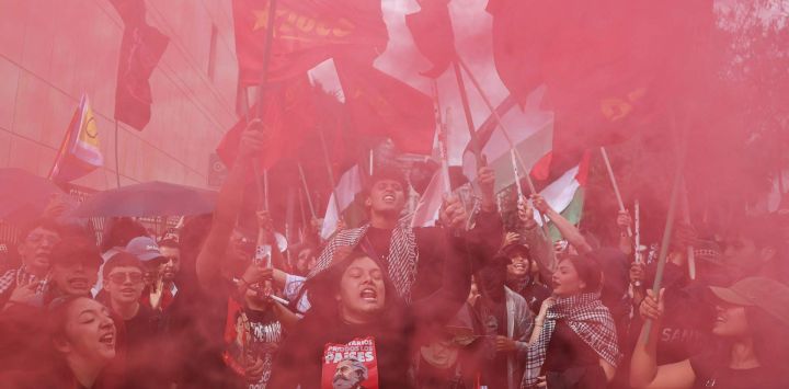 Los manifestantes aparecen envueltos en humo rojo proveniente de bengalas durante una protesta contra el gobierno del presidente colombiano Abelardo de la Espriella, en Bogotá, en el marco de una jornada nacional de manifestaciones convocada por sindicatos, organizaciones de docentes, grupos estudiantiles y sectores de la oposición.