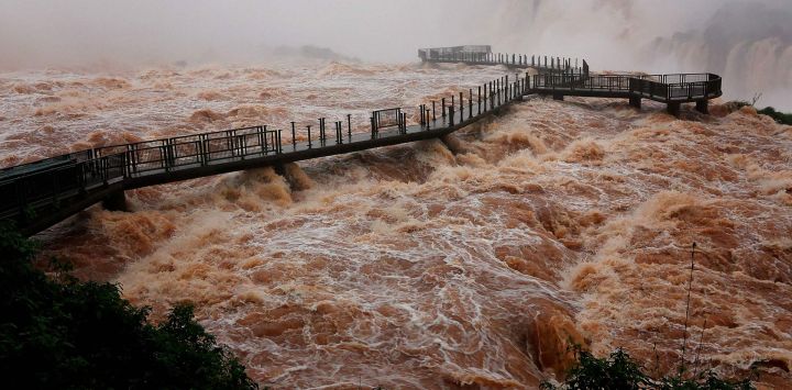 Una vista general muestra la pasarela para visitantes en las cataratas del Iguazú, situada sobre una fuerte corriente, vista desde el lado brasileño —en la triple frontera entre Brasil, Argentina y Paraguay—, en la ciudad de Foz do Iguaçu, estado de Paraná, Brasil. Las autoridades cerraron temporalmente el acceso turístico a las cataratas del Iguazú debido a la crecida del río homónimo; asimismo, se ha registrado un aumento en el caudal de los ríos Paraná y Uruguay, consecuencia de las lluvias asociadas al fenómeno de El Niño.
