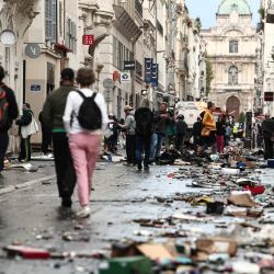 Unos peatones caminan por una calle cubierta de escombros, un día después de las protestas a nivel nacional contra el "alto costo de la vida", en Marsella. El primer ministro de Francia informó que 1200 personas fueron detenidas durante las protestas en todo el país y que 150 agentes de policía resultaron heridos en los enfrentamientos entre las fuerzas de seguridad y los manifestantes. Saqueos masivos e incendios múltiples se extendieron por Francia, a medida que las marchas nacionales contra la inflación desbocada degeneraban en una violencia callejera de extrema intensidad. | Foto:Thibaud Moritz / AFP