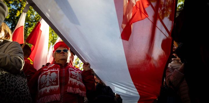 Los participantes sostienen banderas nacionales de Polonia durante una manifestación antigubernamental frente al Tribunal Constitucional en Varsovia. Manifestantes de derecha mantienen una acampada de protesta en el exterior del edificio del Tribunal Constitucional, en Polonia, para protestar contra el nombramiento de nuevos jueces y en defensa de aquellos designados por el anterior gobierno del partido Ley y Justicia (PiS).