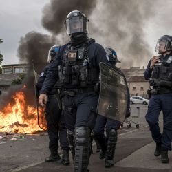 Agentes de la policía antidisturbios pasan junto a basura en llamas mientras manifestantes y estudiantes de secundaria se reúnen frente al liceo Toulouse-Lautrec, en Toulouse. Desde finales de septiembre, los alumnos han bloqueado las entradas de cientos de centros educativos, denunciando la ausencia de profesores, horarios sobrecargados, aulas en mal estado y edificios mal adaptados al aumento de las temperaturas, entre otras quejas. | Foto:ED JONES / AFP