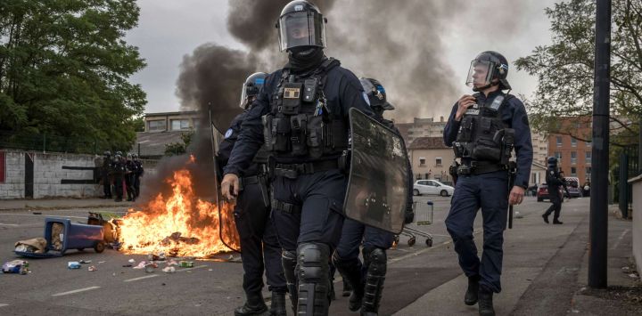 Agentes de la policía antidisturbios pasan junto a basura en llamas mientras manifestantes y estudiantes de secundaria se reúnen frente al liceo Toulouse-Lautrec, en Toulouse. Desde finales de septiembre, los alumnos han bloqueado las entradas de cientos de centros educativos, denunciando la ausencia de profesores, horarios sobrecargados, aulas en mal estado y edificios mal adaptados al aumento de las temperaturas, entre otras quejas.