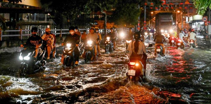 Motociclistas circulan por una calle inundada debido a mareas altas en Ciudad Ho Chi Minh, Vietnam.