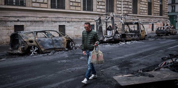 Un hombre pasa junto a una hilera de vehículos calcinados en la Rue Yves Toudic, destruidos tras una protesta a escala nacional contra el "alto costo de la vida" en el centro de París. El primer ministro de Francia informó que 1.200 personas fueron detenidas durante las protestas celebradas en todo el país que 150 agentes de policía resultaron heridos en los enfrentamientos con los manifestantes. Saqueos masivos e incendios múltiples se extendieron por Francia, a medida que las marchas nacionales contra la inflación desbocada degeneraban en una violencia callejera de extrema intensidad.