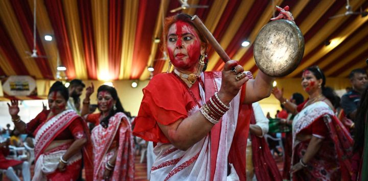 Devotos hindúes bailan mientras mujeres casadas se untan mutuamente con polvo de bermellón durante el ritual "Sindoor Khela", en el último día del festival Durga Puja, en Ahmedabad.