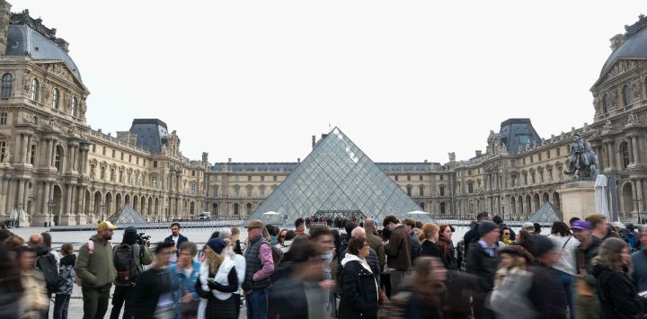 Turistas se reúnen frente al Museo del Louvre, en París, Francia.