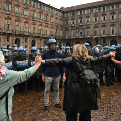 Profesores se sitúan entre la policía antidisturbios y los estudiantes en la Piazza Castello, en el centro de Turín, durante el "No Meloni Day" —una jornada nacional de marchas en toda Italia, inspirada en lo que ocurre en Francia y España—, para protestar contra el costo de la vida, el "Decreto Escolar" y el estado de los edificios escolares, además de exigir un aumento de la financiación. | Foto:MARCO BERTORELLO / AFP