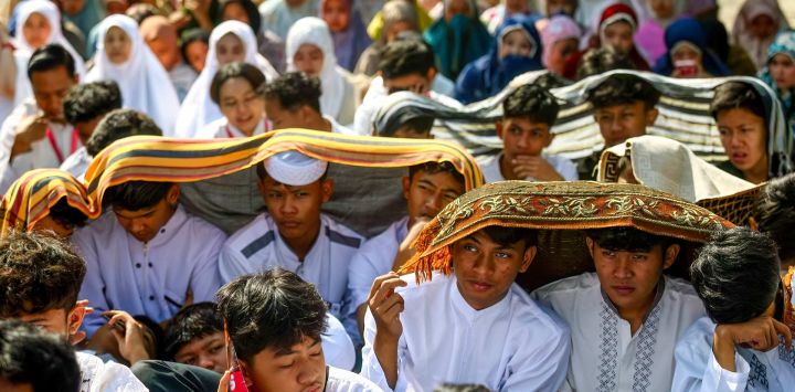 Estudiantes y residentes se protegen del sol mientras participan en la ceremonia de oración *Istisqa* —una plegaria para pedir lluvia— en medio de una prolongada sequía provocada por el fenómeno de El Niño, en Malang, provincia de Java Oriental, Indonesia.