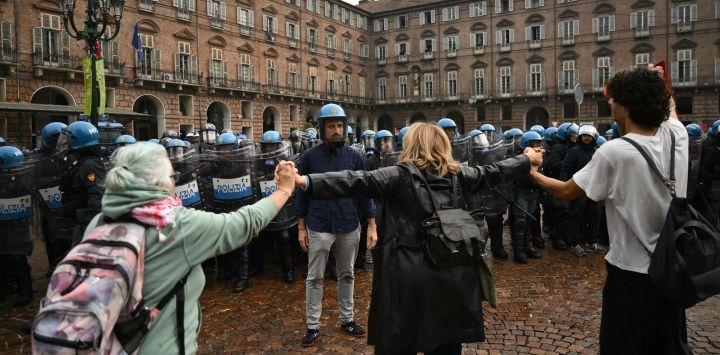 Profesores se sitúan entre la policía antidisturbios y los estudiantes en la Piazza Castello, en el centro de Turín, durante el "No Meloni Day" —una jornada nacional de marchas en toda Italia, inspirada en lo que ocurre en Francia y España—, para protestar contra el costo de la vida, el "Decreto Escolar" y el estado de los edificios escolares, además de exigir un aumento de la financiación.