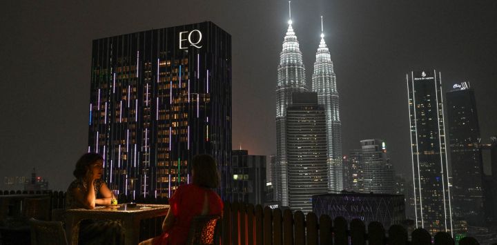 Unas mujeres están sentadas en un bar en una azotea frente a las Torres Gemelas Petronas en Kuala Lumpur, mientras el país sigue envuelto en una bruma causada por incendios en Indonesia.