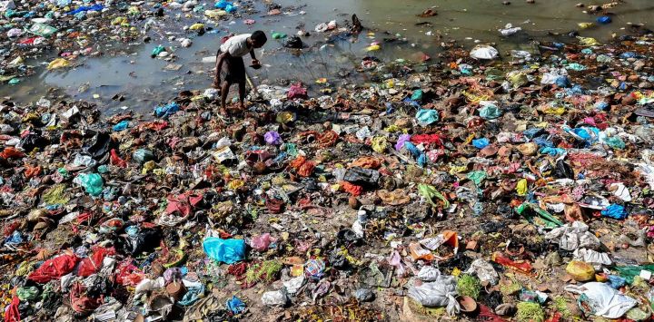 Una persona que recolecta materiales reciclables busca entre la basura, a lo largo de un canal en Amritsar, objetos aprovechables y dinero que la gente ha arrojado como parte de ofrendas rituales.